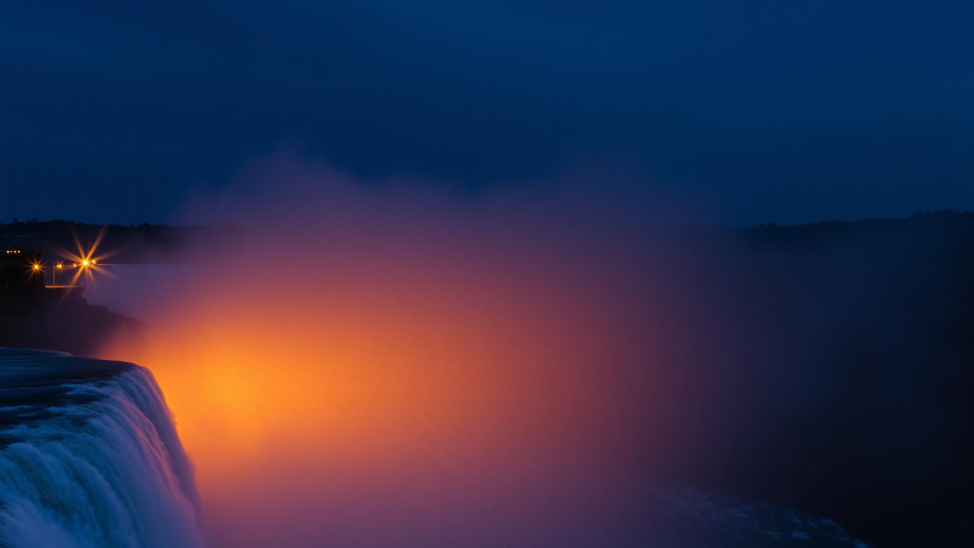 Aerial view of Niagara Falls illuminated at twilight with mist rising over the Horseshoe Falls